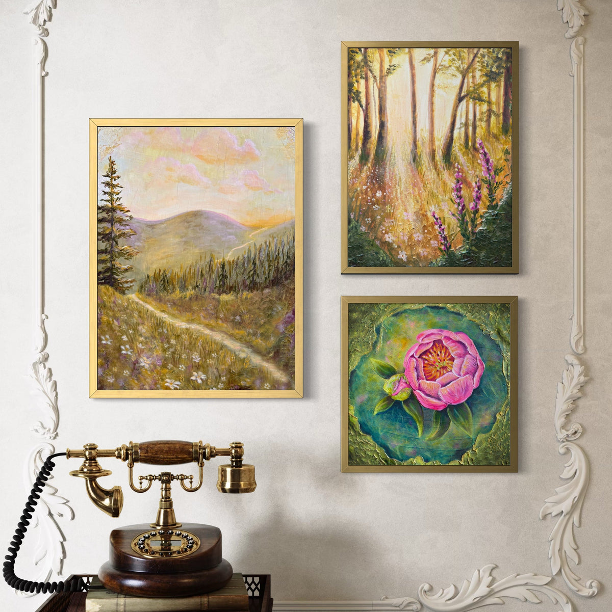Three framed art prints displayed on a white wall with decorative molding and a vintage wooden table holding a dark brown rotary telephone. The prints depict a mountain landscape, a sunlit forest, and a pink peony flower.